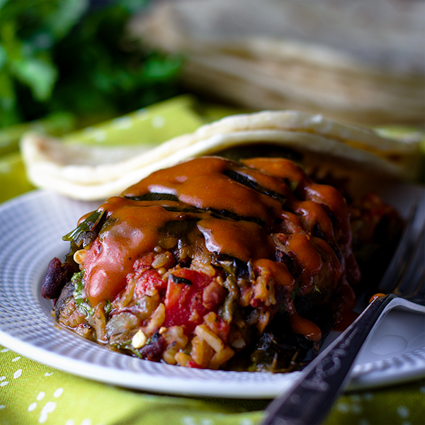 A stuffed poblano pepper with enchilada sauce.