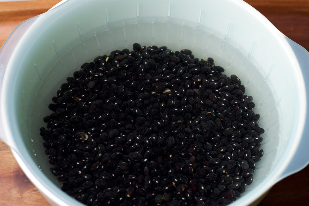 Black beans soaking in a bowl of water before cooking.