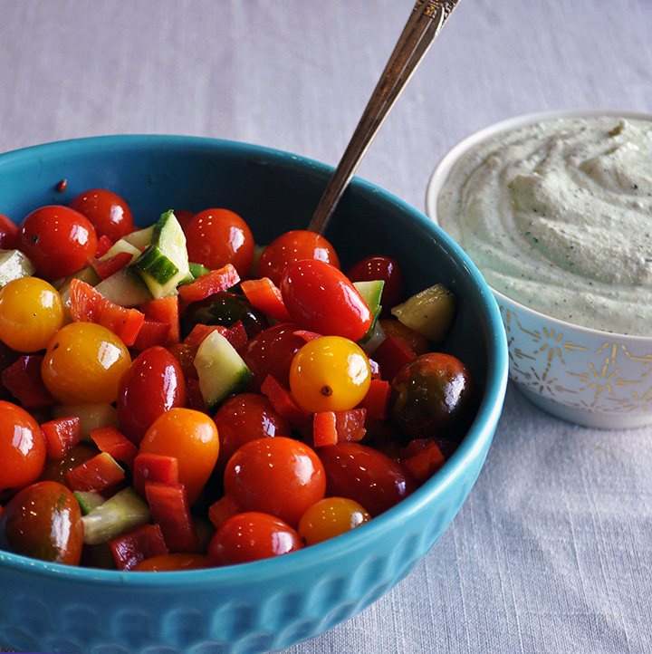 A bowl of tomato cucumber salad with basil whipped ricotta.