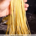 Someone holding up freshly cut homemade spaghetti noodles.
