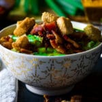A bowl of Cream of Asparagus Soup topped with croutons and bacon.