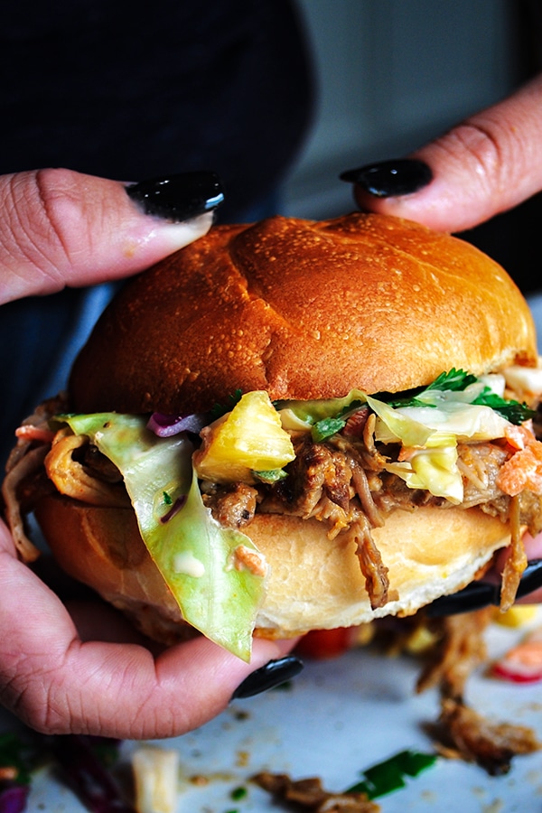 Holding a pulled pork sandwich with pineapple coleslaw.