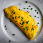 A French omelette filled with Boursin cheese on a plate, ready to eat.