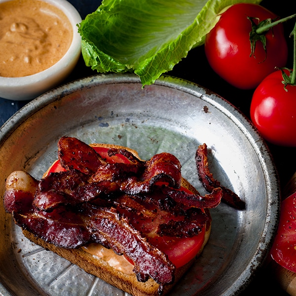 Bacon and tomatoes on toast for a BLT sandwich.