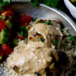 Tahini Grilled Chicken with Couscous on a plate with tomato and cucumber salad.