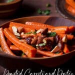 A wooden bowl filled with roasted carrots and dates topped with chopped almonds.
