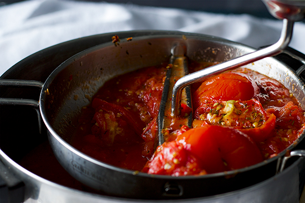 Pushing roasted tomatoes through a food mill to make Roasted Tomato Sauce with Garlic and Herbs