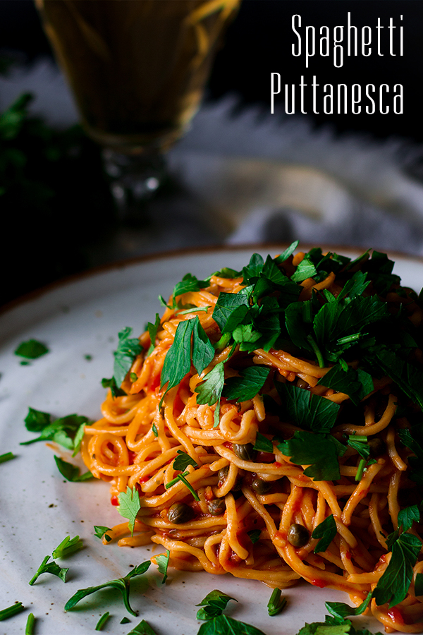 A plate of Spaghetti Puttanesca topped with parsley.