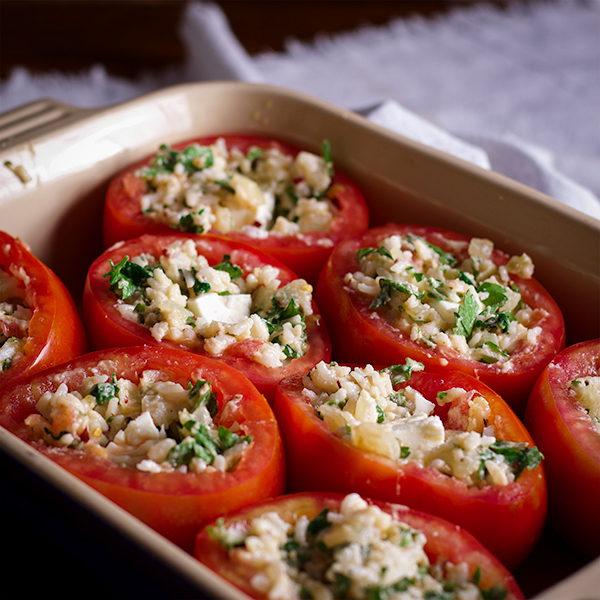 A baking dish filled with cheese stuffed tomatoes ready to be baked.