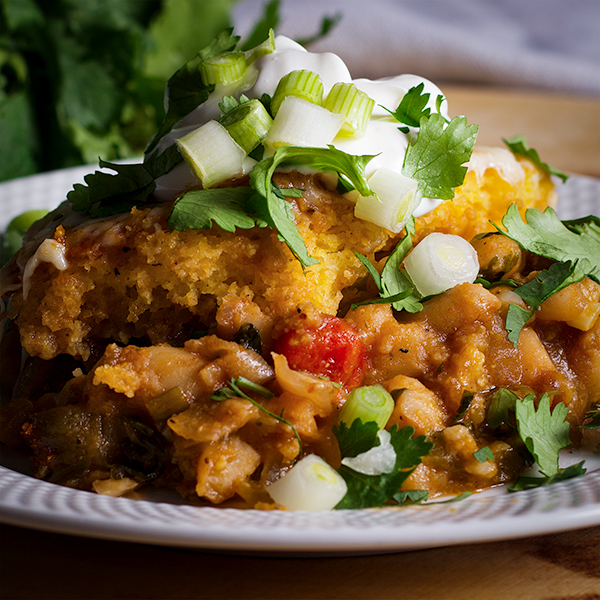 A plate of tamale pie with white beans, chorizo, salsa verde and cheese