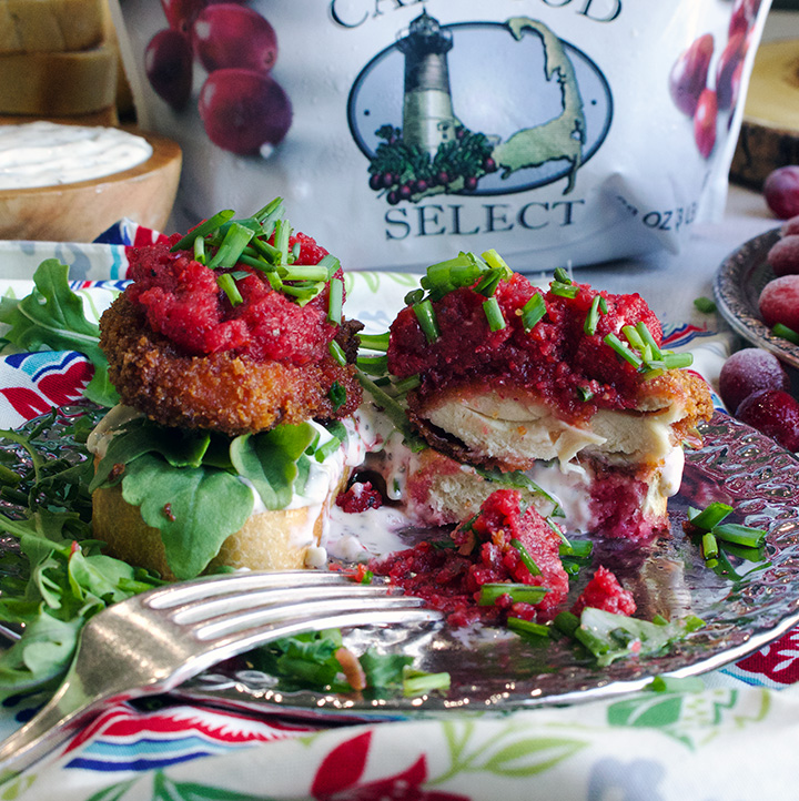 Cutting into a fried chicken sandwich with savory mayonnaise, arugula, and spicy cranberry relish.