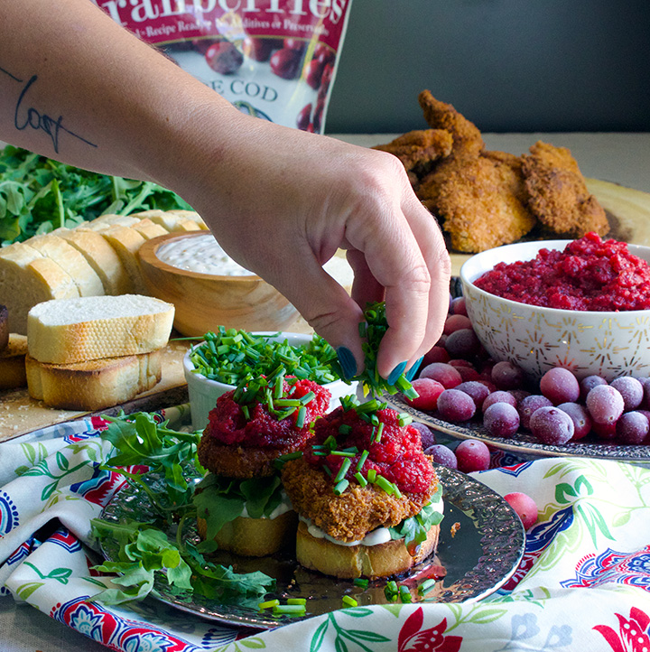 Sprinkling chives over Fried chicken sandwiches with savory mayonnaise, arugula, and spicy cranberry relish.