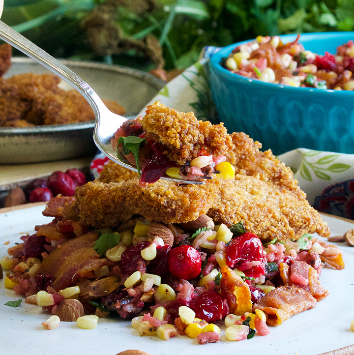 Taking a bite of Wild rice, cranberry and corn salad with fried chicken.