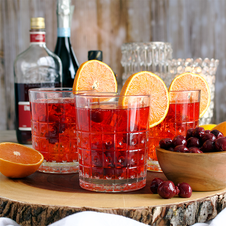 A tray with three glasses of Cherry Citrus Prosecco Spritz cocktails.