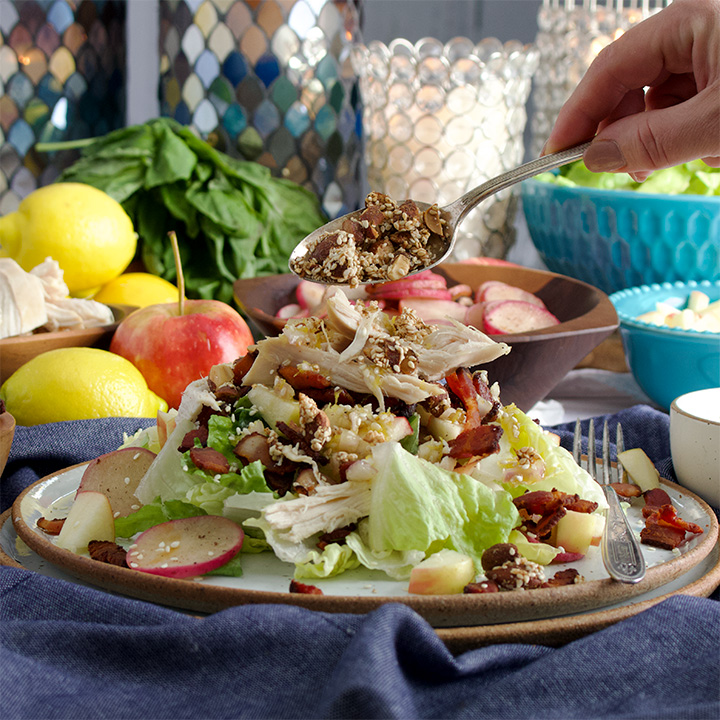 Sprinkling sesame crunch over Roast Chicken Salad with Lemon Vinaigrette, Bacon, Radishes, and Apples.