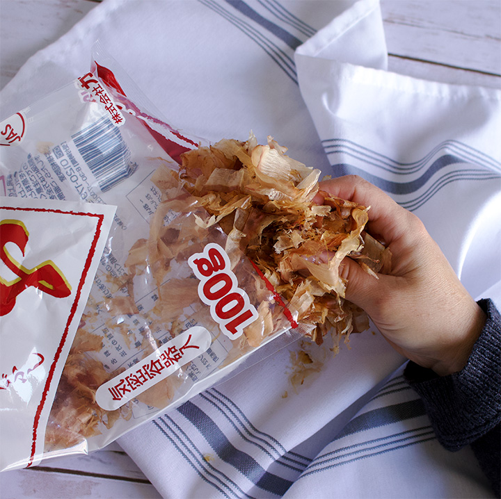 Removing dried bonito flakes from a bag.