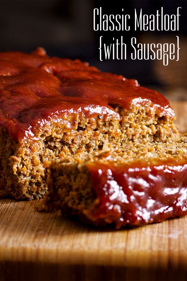 A freshly baked meatloaf covered in a tangy ketchup glaze resting on a wood cutting board. The meatloaf has been cut in half so you can see the moist, tender middle. 