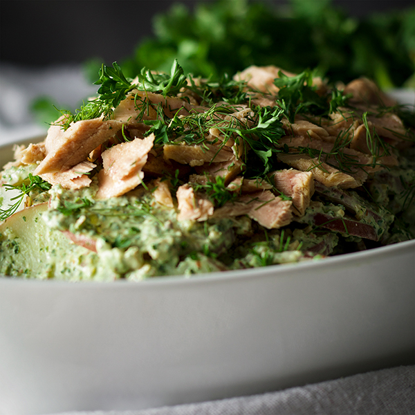 A bowl of potato salad with creamy avocado and herb green sauce and tuna fillets.