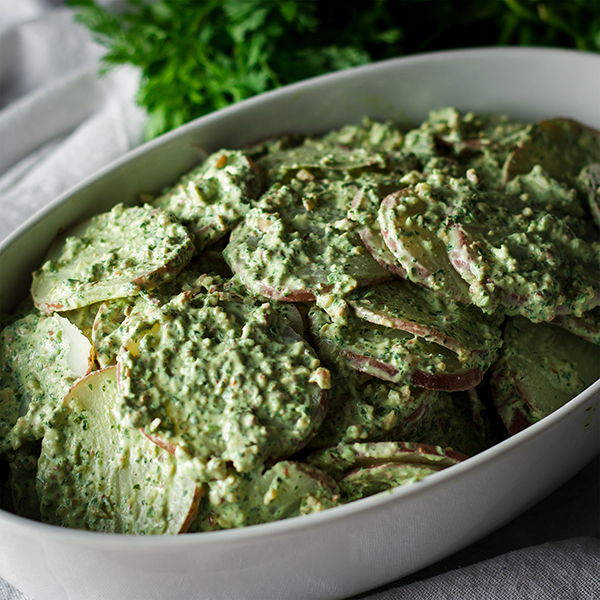 A bowl of potato salad with creamy avocado and herb green sauce.