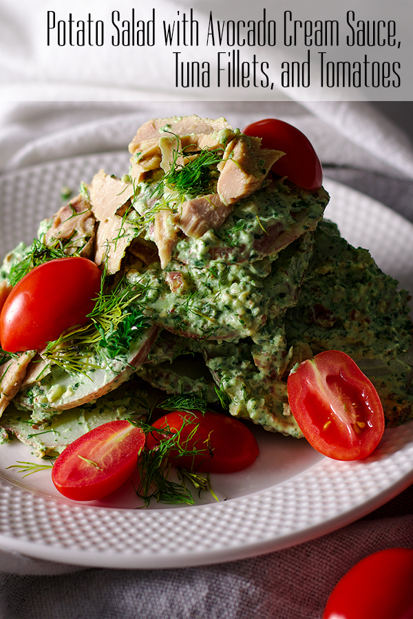 A plate of potato salad with creamy avocado and herb green sauce, tuna fillets and tomatoes
