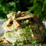 A plate of potato salad with creamy avocado and herb green sauce and tuna fillets.
