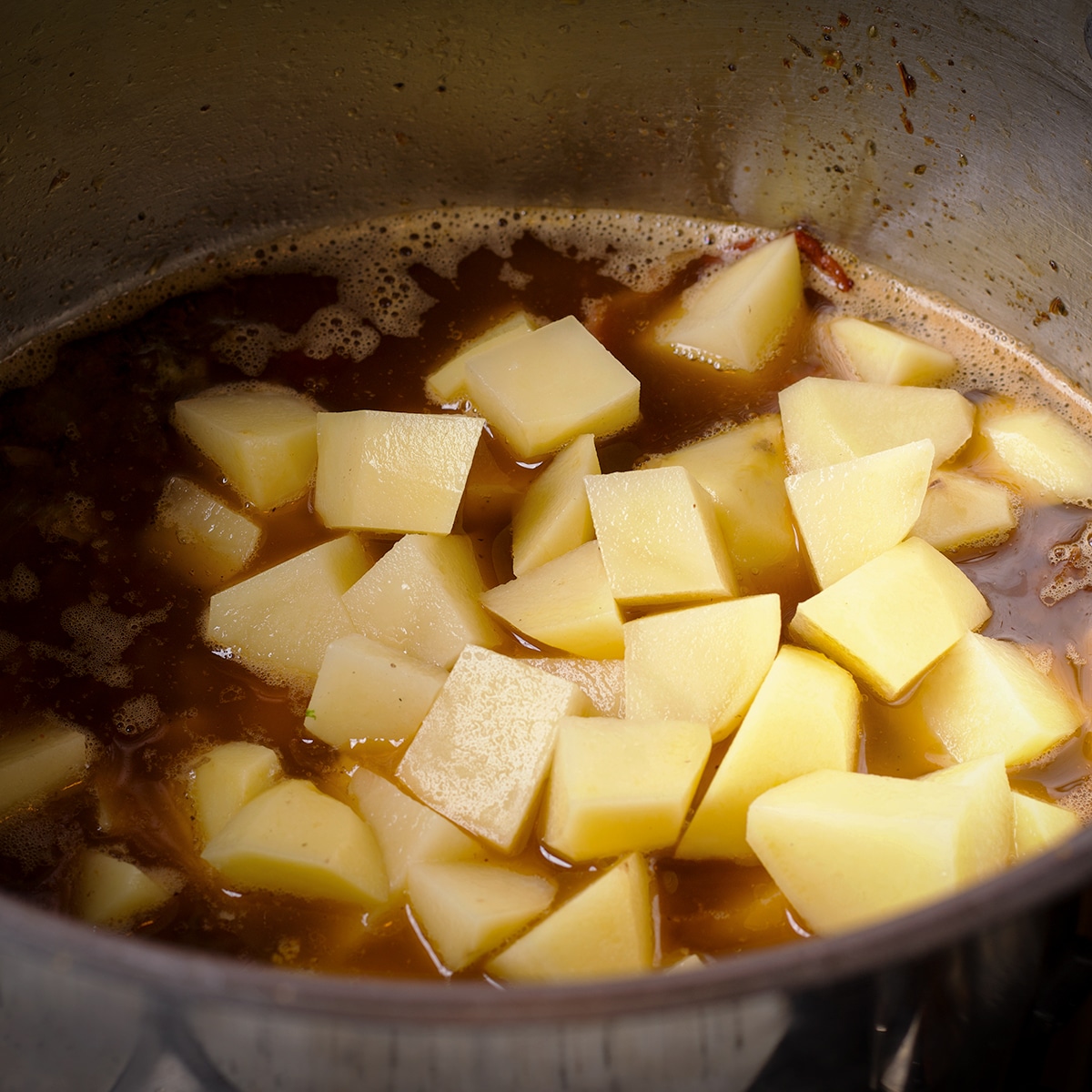 Adding chopped yellow potatoes to the broth with the sausage and bacon.