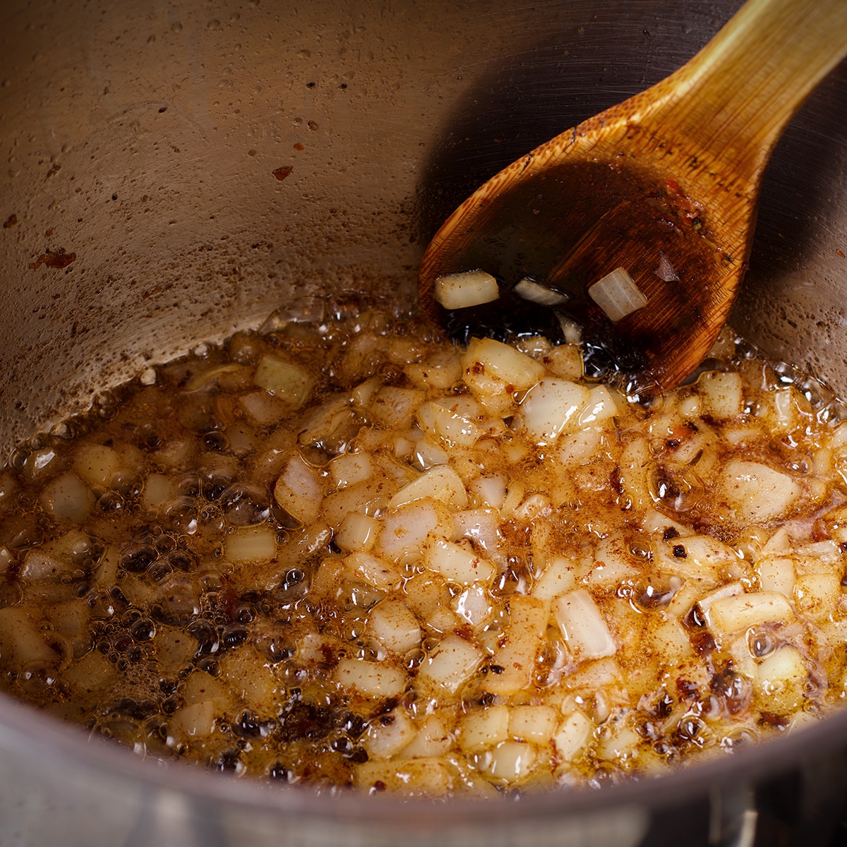 Chopped onion, garlic, and spices cooking in hot oil in a large saucepan.
