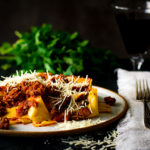 A plate of pasta bolognese with pappardelle pasta and parmesan cheese.