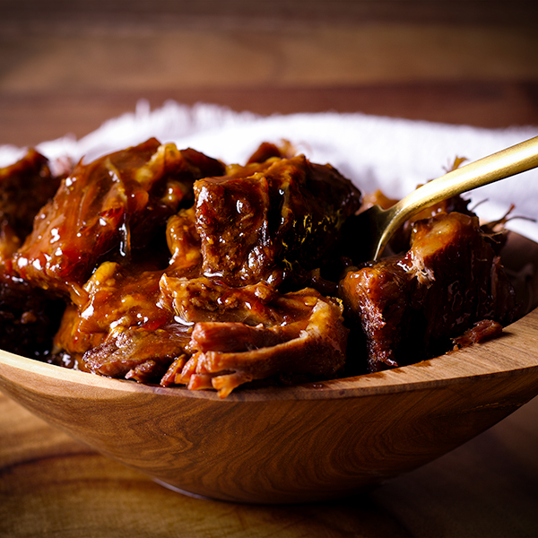 A bowl of Asian short rib meat with a fork, ready to eat.