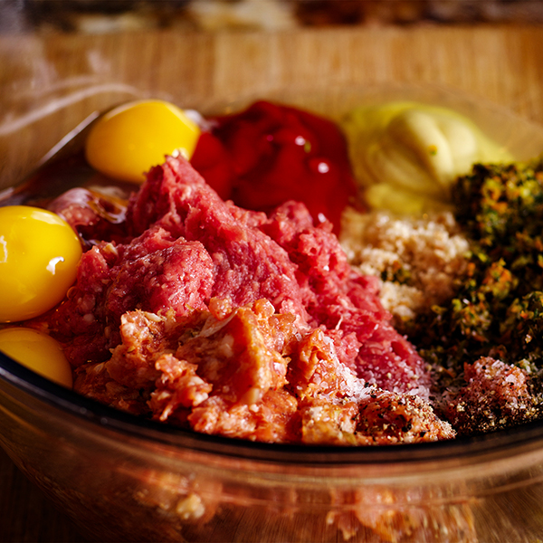 A glass bowl that contains all the ingredients for meatloaf.