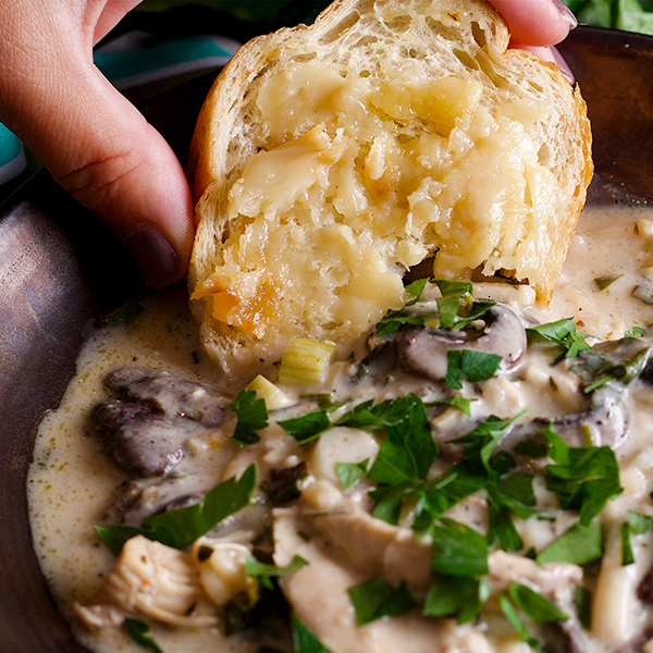 Dipping a piece of bread into a bowl of Creamy Chicken and Mushroom Soup.