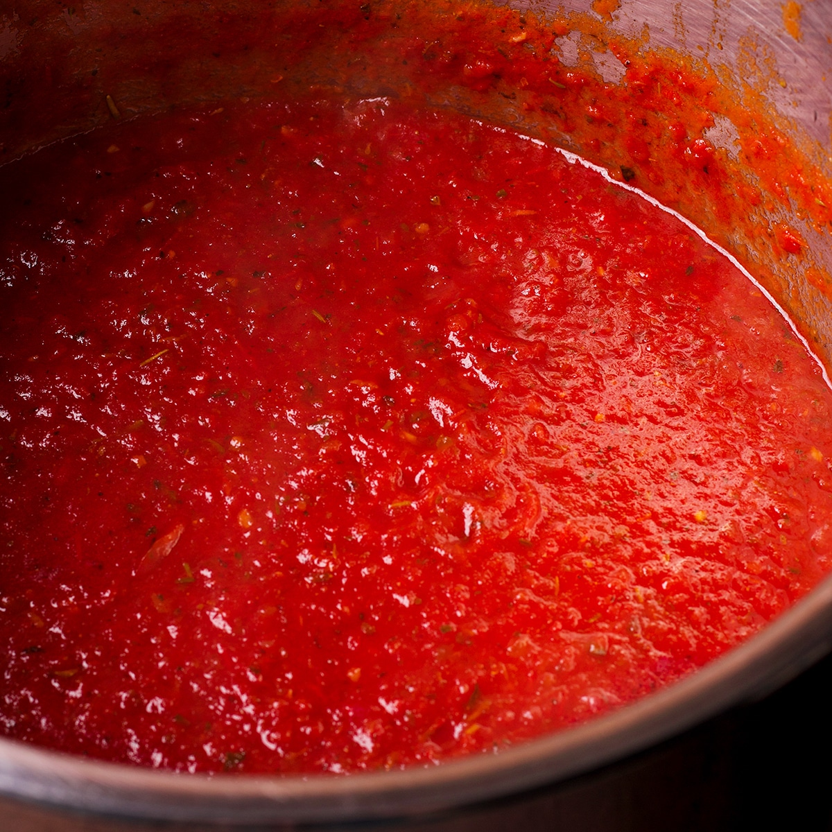 Marinara sauce in a large saucepan simmering on the stovetop.