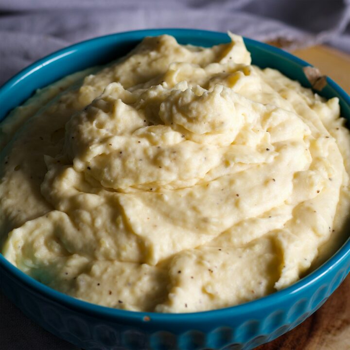 A blue bowl filled with cream cheese mashed potatoes.