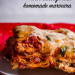 Using a spatula to set a slice of homemade lasagna with sausage on a plate.
