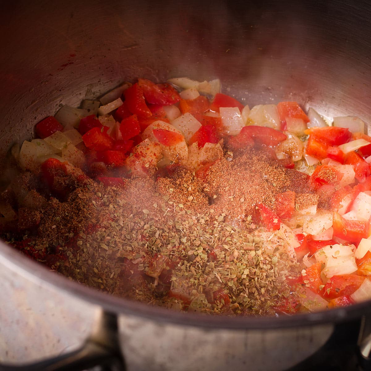 Add garlic, cumin, oregano, paprika, cayenne, salt and pepper to the onions and red bell pepper while they cook.