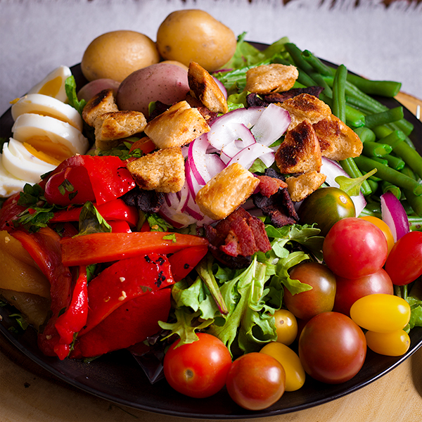 A Niçoise Salad assembled on a dinner plate and ready to eat.