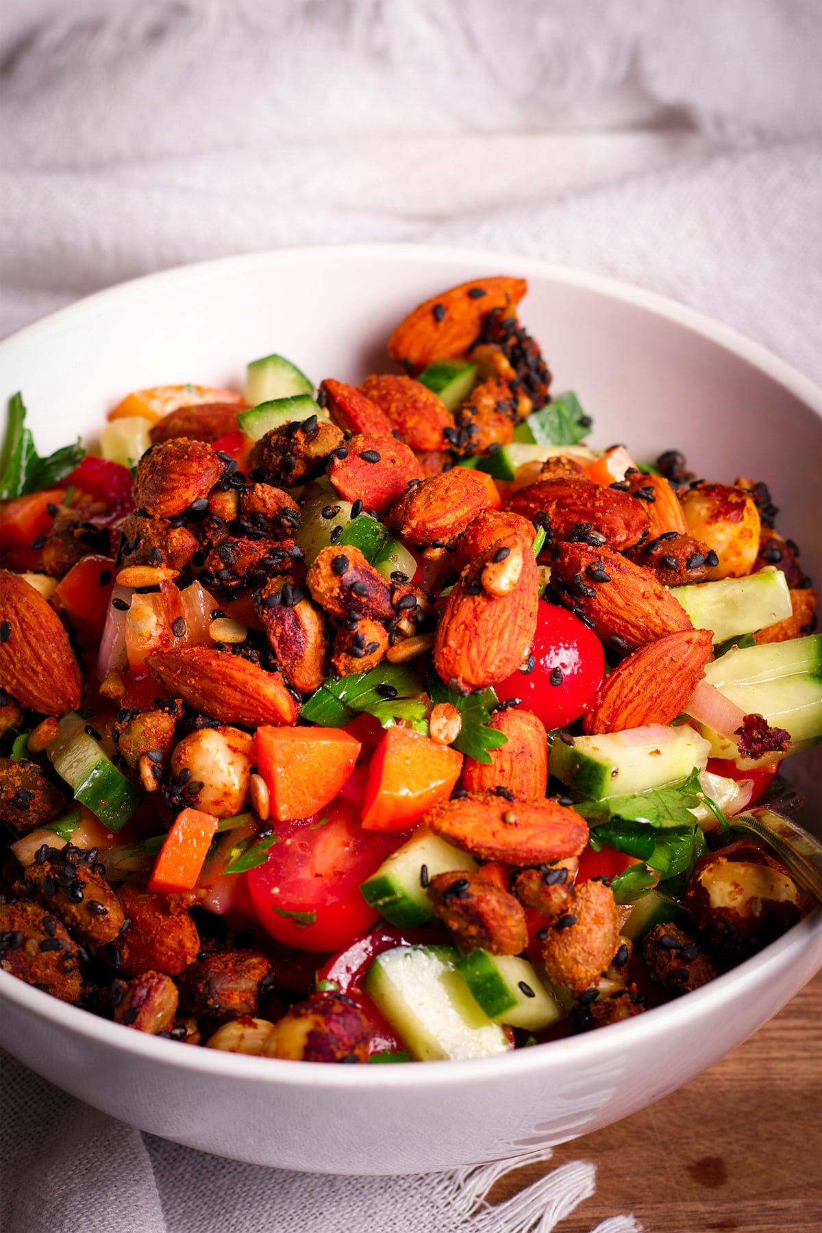 A bowl of Israeli Salad topped with roasted nuts and seeds.