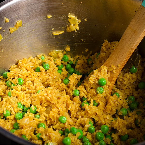 Stirring a pot of Indian Rice with peas.