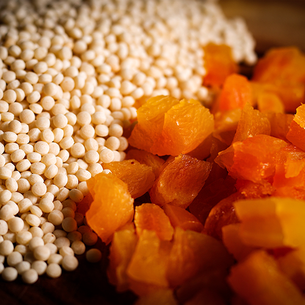 Pearl couscous and dried apricots on a cutting board.