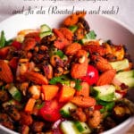 A bowl of Israeli Salad topped with roasted nuts and seeds.