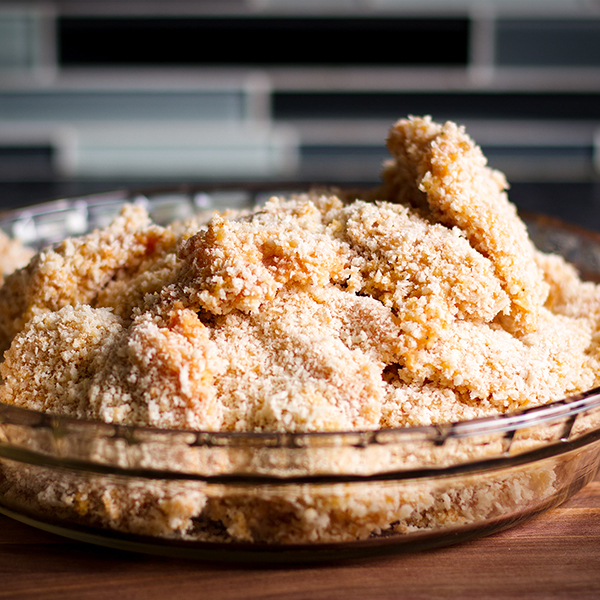 A plate of chicken, coated in breading and ready to be fried.