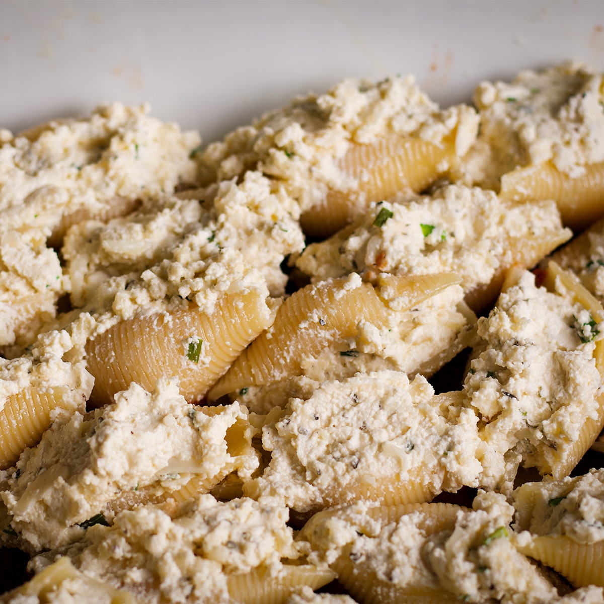 A casserole dish filled with pasta shells stuffed with ricotta cheese mixture.