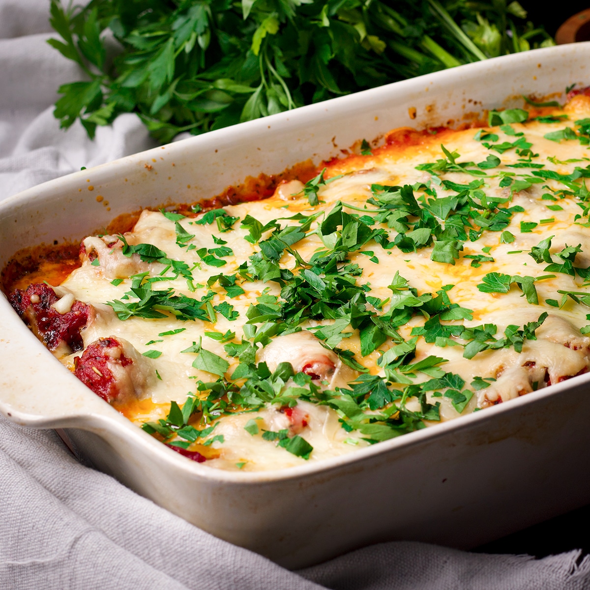 A pan of freshly baked three cheese ricotta stuffed shells with chopped parsley sprinkled over the top.