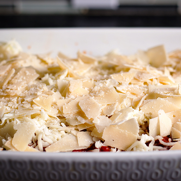 A pan of stuffed pasta shells covered in marinara sauce and grated mozzarella and parmesan cheese.