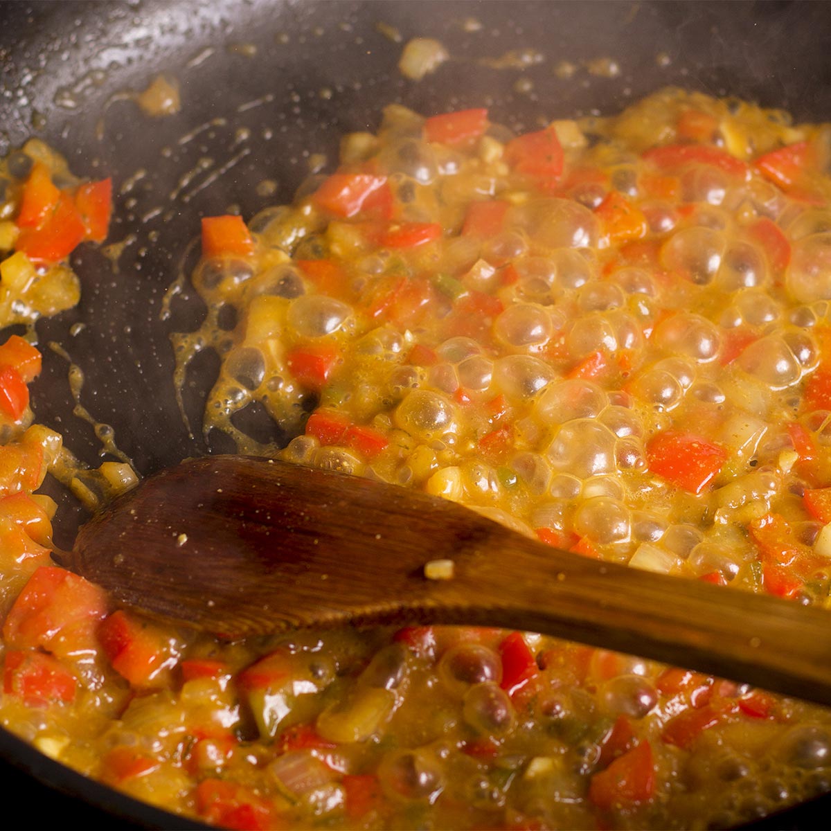 Pour chicken stock into the skillet with the vegetables and let it cook while stirring.