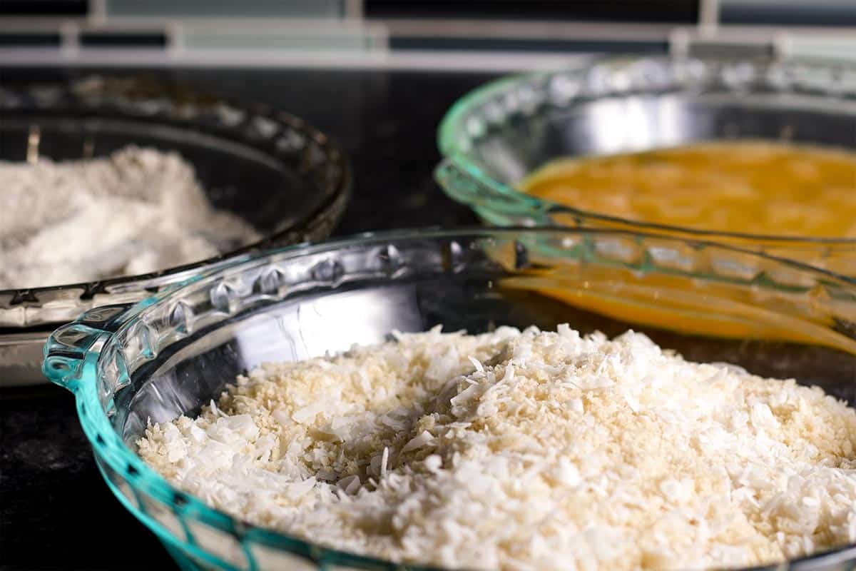 Three pie plates filled with the ingredients needed to coat chicken with breading.