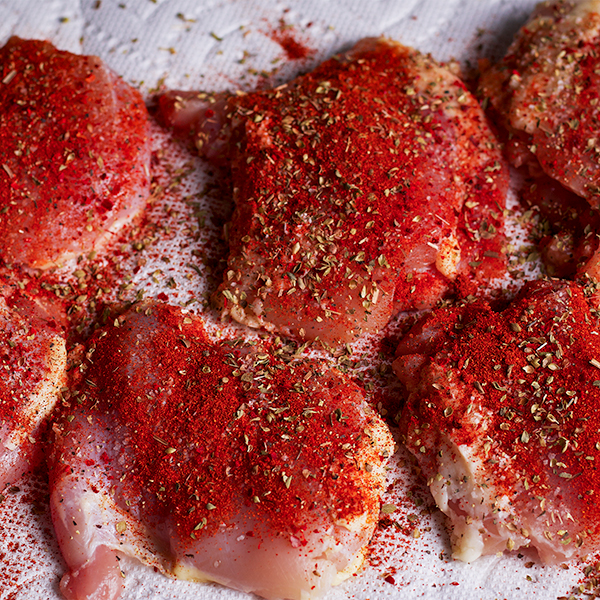 Preparing chicken for The Ultimate Sheet Pan Dinner by rubbing it with spices.