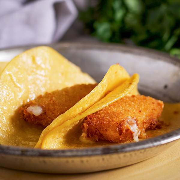 Breaded, fried cheese in corn tortillas on a plate.