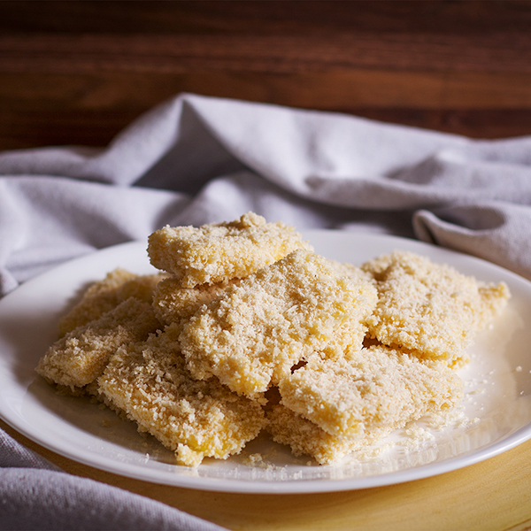A plate of breaded cheese, ready to be fried.