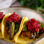 Three shishito pepper tacos with fried cheese and chili cranberry sauce on a plate.